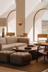 A modern living room with neutral-toned fabrics and wooden furniture, featuring a comfortable seating area and a low coffee t