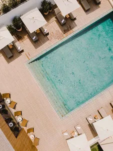Swimming pool deck with wooden flooring, lounge chairs, and umbrellas.