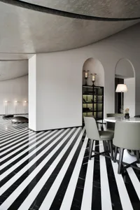 A modern dining room with concrete walls, marble flooring, and a round table with chairs.