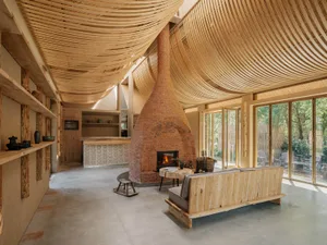 A modern industrial living room with wooden elements, a brick fireplace, and large windows.