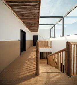 A modern minimalist interior design featuring a wooden staircase with glass railings and a textured ceiling.