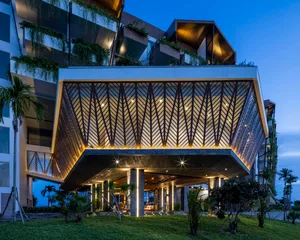 A modern residential building entrance featuring an aluminum-framed canopy with a geometric design.