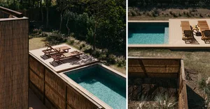 A wooden pool deck area surrounded by greenery and plants.