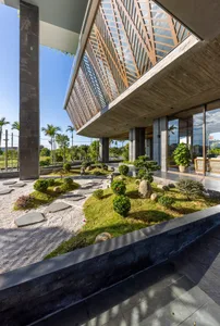 Modern architectural design featuring concrete exterior, glass walls, and bamboo plants.