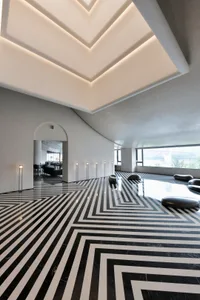 A modern interior with a lobbly featuring hidden lighting, black and white marble tiles, and minimalist design