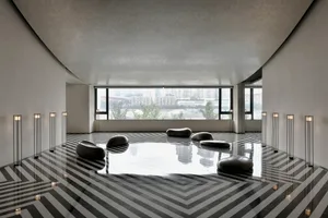 Modern lobby with minimalist design featuring glass walls and concrete floor.