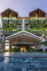 A modern hotel facade with wooden balconies covered in green plants.