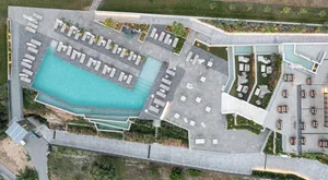 Luxury hotel resort with indoor and outdoor spaces, featuring a swimming pool, lounge chairs, and dining areas.