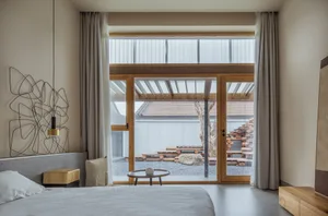 Minimalist bedroom featuring concrete floor, wooden bed frame, and glass windows