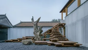 A minimalist outdoor space featuring wood, stone, and metal elements.