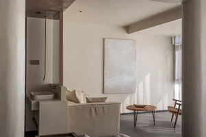 Modern minimalist living room featuring a concrete wall with a large abstract wall art piece and a small wooden coffee table.