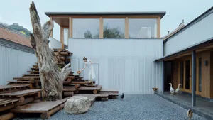 A minimalist metal-clad exterior with wooden steps and a stone path.