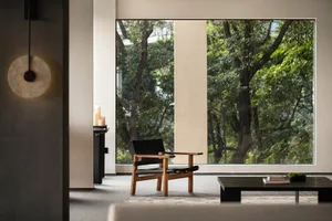 Modern living room featuring wooden chair, leather cushion, and concrete elements