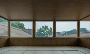 A modern minimalist living room with a wooden floor and sliding glass doors.