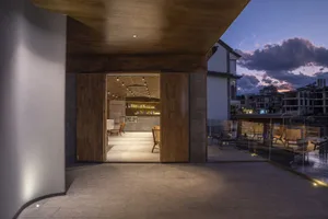 Modern restaurant bar with wooden panels, concrete floor, and metal accents.