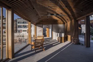 A cozy, industrial-style front porch features wooden framing, concrete flooring, and a brick fireplace, providing a warm and 