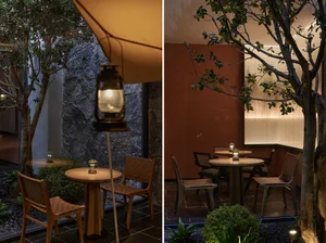 Industrially designed restaurant seating area with wooden tables and chairs, a lantern, and greenery.