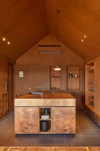 A minimalist kitchen with wooden finishes and a central island.