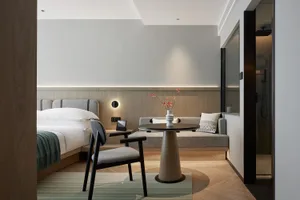 Modern minimalist bedroom and living area layout with wooden furniture, fabric seating, and glass shower enclosure.