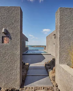 An modern exterior facade with concrete walls and a glass pool.