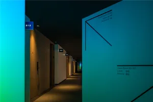 A modern hotel hallway illuminated with warm lighting, featuring room signs and directional arrows.