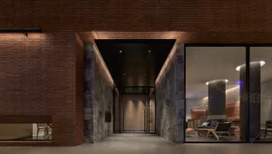 Modern hotel lobby with brick walls and concrete pillars, illuminated by warm lighting.