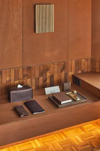 A modern hotel reception desk with wooden elements and a tray of notepads and cards.