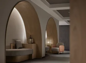 A modern minimalist hotel treatment room with wooden accents and cozy seating arrangements.