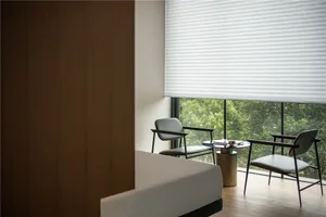 A modern minimalist living room with white furniture and a large window overlooking greenery.