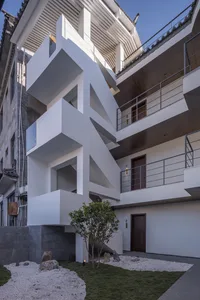 Modern residential exterior featuring minimalist design with white concrete walls and glass elements.