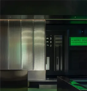 A storefront with metallic panels and green neon signs.