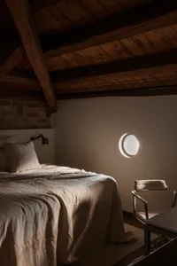 Industrial-style bedroom with exposed wooden beams on the ceiling and a small round window.