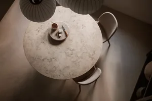 Modern interior design featuring a round marble table with minimalist chairs and a minimalist table centerpiece.