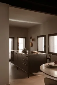 A modern, minimalist kitchen featuring a metal kitchen island.