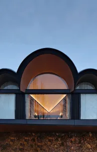 Modern interior design featuring a glass window with warm lighting, set against a clear blue sky.