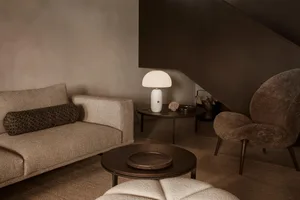 A modern living room featuring a couch, armchair, coffee table, and a marble table lamp.