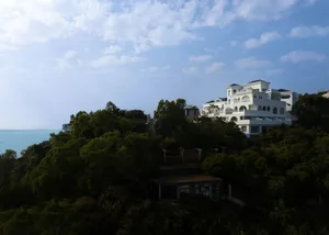 Modern villas with white concrete and glass on a hillside overlooking the sea.