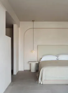 Minimalist bedroom with concrete sconce and concrete floor.