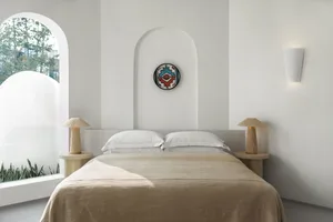 Modern, minimalist bedroom with textured wallpaper, white walls, and a cozy bed setup.