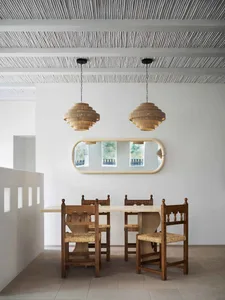 Minimalist dining room featuring woven chairs, a tiled floor, and a wooden table.