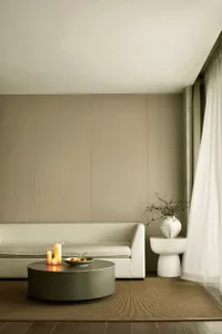 A minimalist living room with light-colored fabric furniture, a plain wooden floor, and a plain light-colored wall.