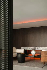 Modern living room with concrete walls and furniture, featuring a black sculptural side table.