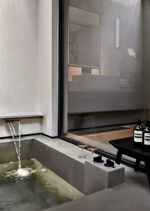 Modern minimalist bathroom with concrete walls, floor, and bathtub, featuring a sleek black faucet and a glass window.