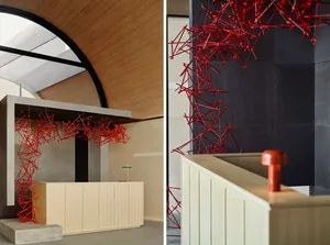 A modern reception desk with a red metallic network design against a dark and white tiled background.