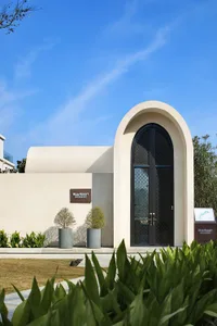 A modern cement entrance featuring an arched door and minimalist design, part of a resort.