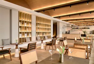 An elegant modern restaurant and bar interior featuring wooden furniture, marble accents, and glass displays.