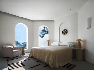 A modern bedroom with white walls, a large bed, and arched windows.