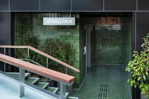 An entrance to a commercial building with green tiles and a handrail.