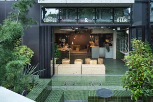 Coffee shop with wooden benches, concrete floor, and glass windows.