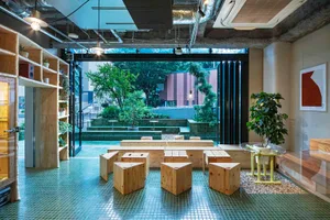 Industrial-style cafe interior featuring wooden furniture and plants.